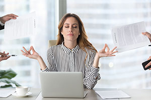 en posture de méditation, cette jeune femme gère le stress que lui apporte son environnement de travail